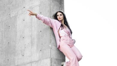 woman in pink coat standing on gray concrete wall